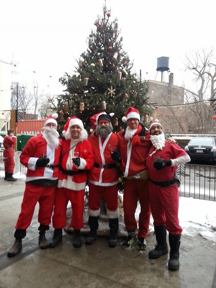 Five original Santa riders posing together by a Christmas tree