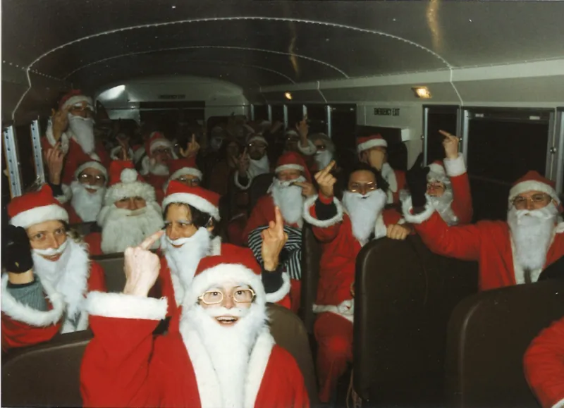 Cacophony Society Cheap Suit Santas making irreverent gestures inside a bus in 1995